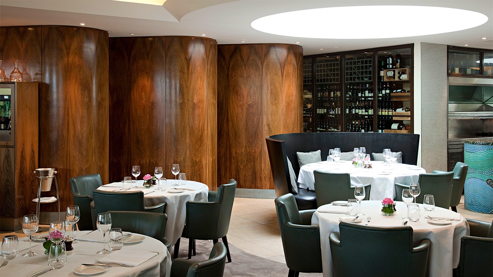 The dining room at Coq d’Argent, with blue leather chairs, wooden columns and a wall of wines on shelves